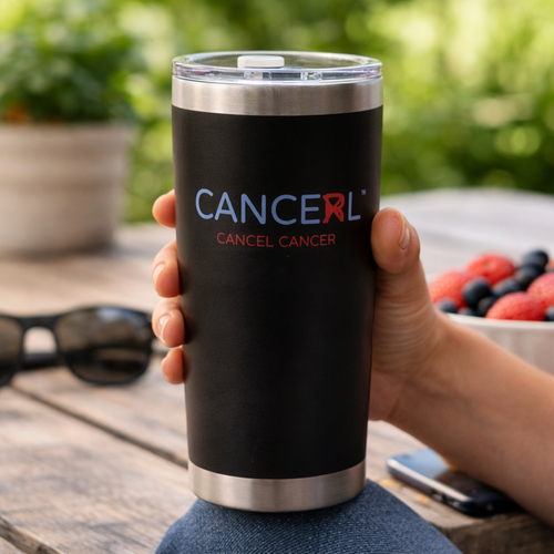Person holding a black tumbler with Cancel Cancer logo outdoors.