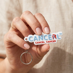 Hand holding a keychain with Cancel Cancer logo